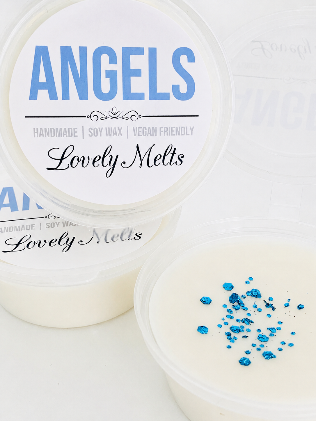Two containers of 'Angels Lovely Melts' with blue specks on a white background