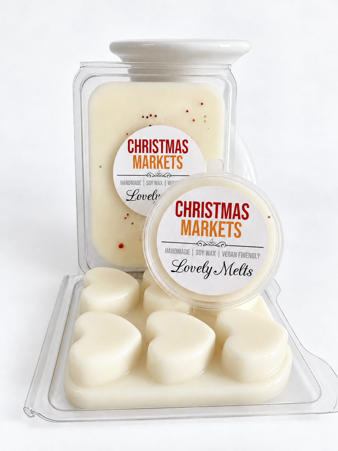 Cream-colored Christmas Markets scented  soy wax melts in a clear plastic tub with heart-shaped melts in front and a larger rectangular melt container behind, both labeled 'CHRISTMAS MARKETS Lovely Melts'.