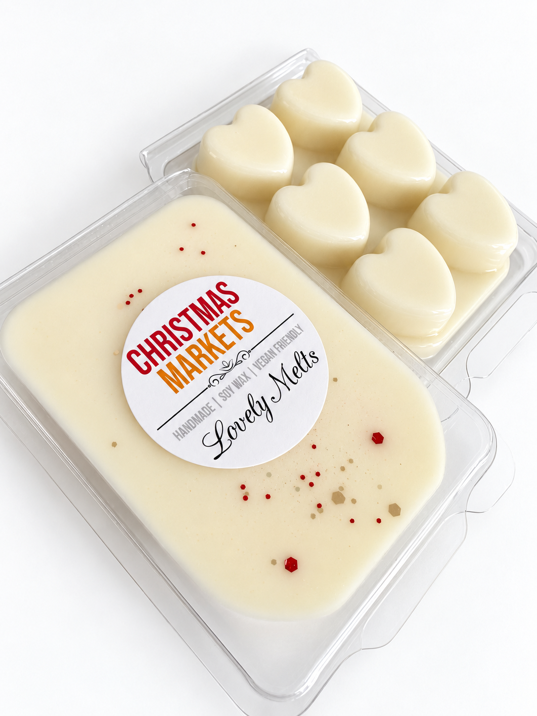 Two clear plastic containers of wax melt bars on a white background. The front container has a cream-colored wax melt with a round white label reading 'Christmas Markets' and small red and gold speckles.