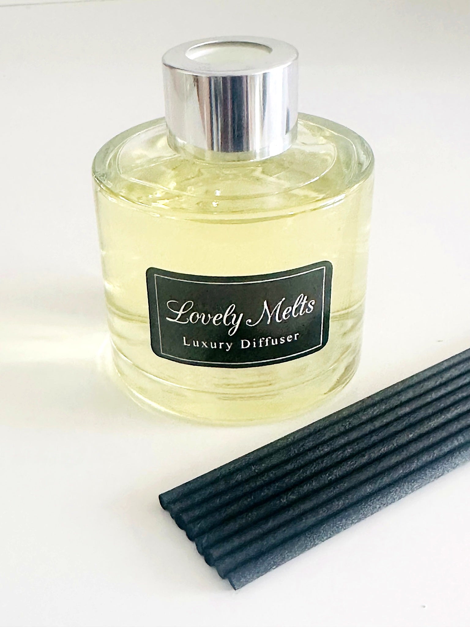 Lovely Melts luxury diffuser with black label and black reeds on a white background