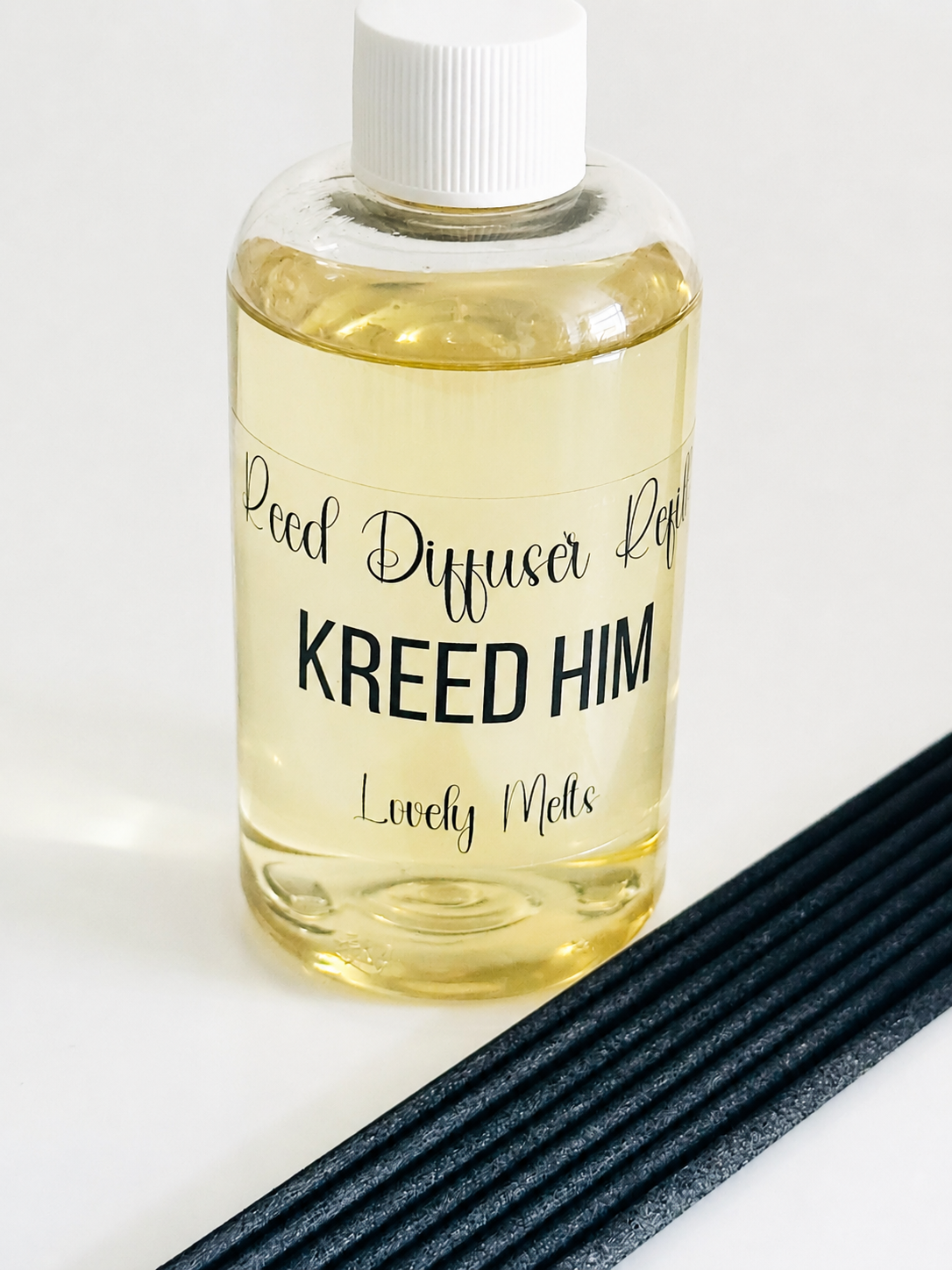 Diffuser oil bottle labeled 'Kreed Him' with black sticks on a white background