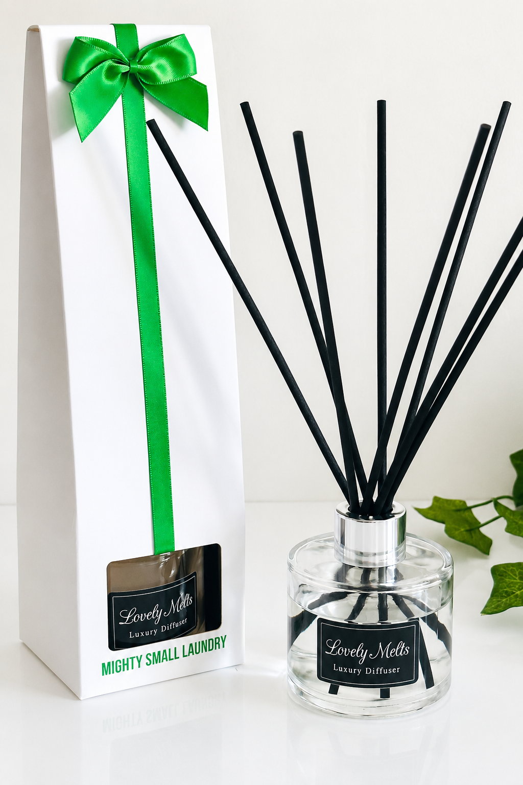 Diffuser with black sticks and a white box with a green bow on a white background