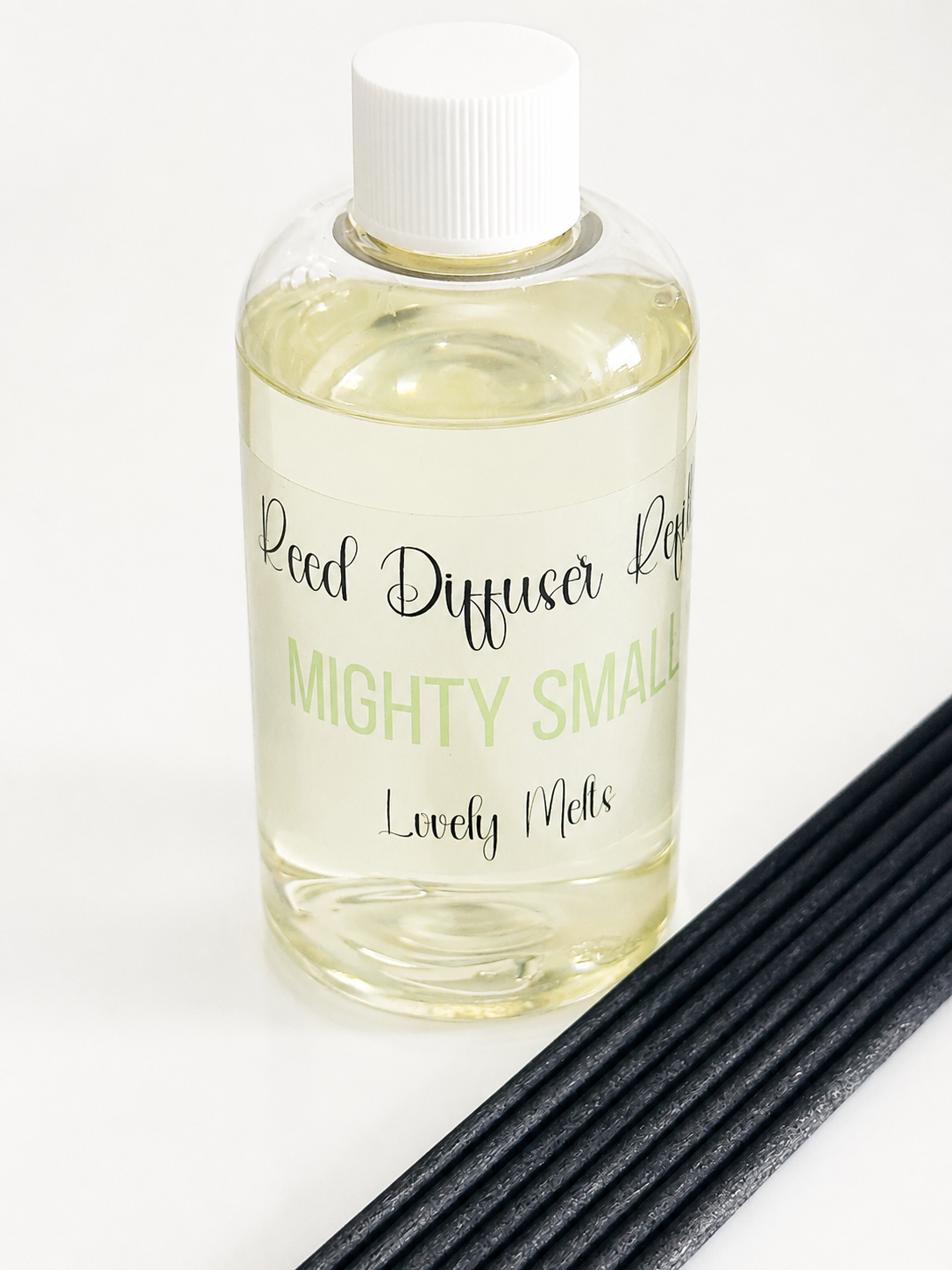 Clear bottle of reed diffuser refill with black reeds on a white background