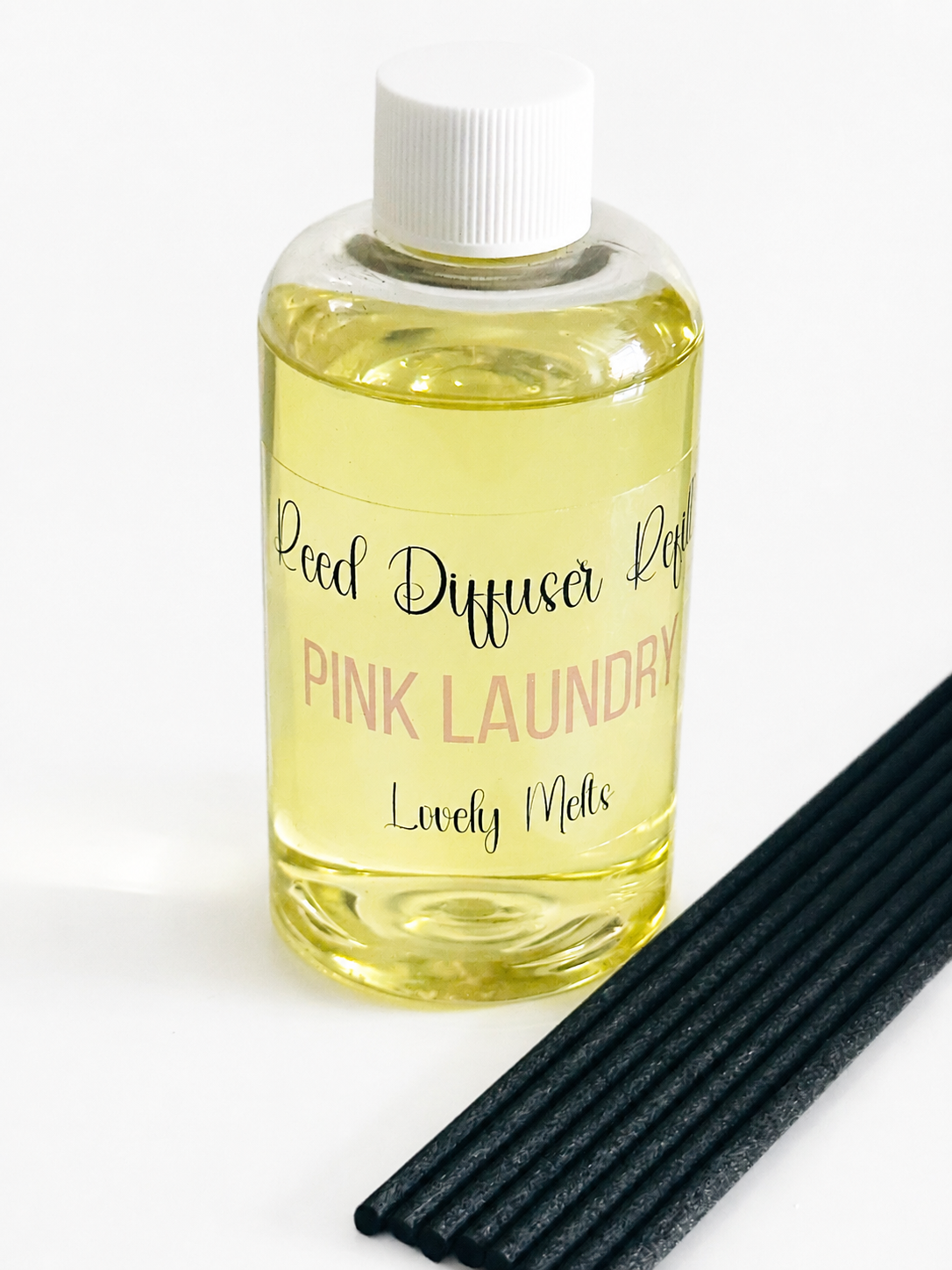 Bottle of 'Pink Laundry' Reed Diffuser Refill with black reeds on a white background