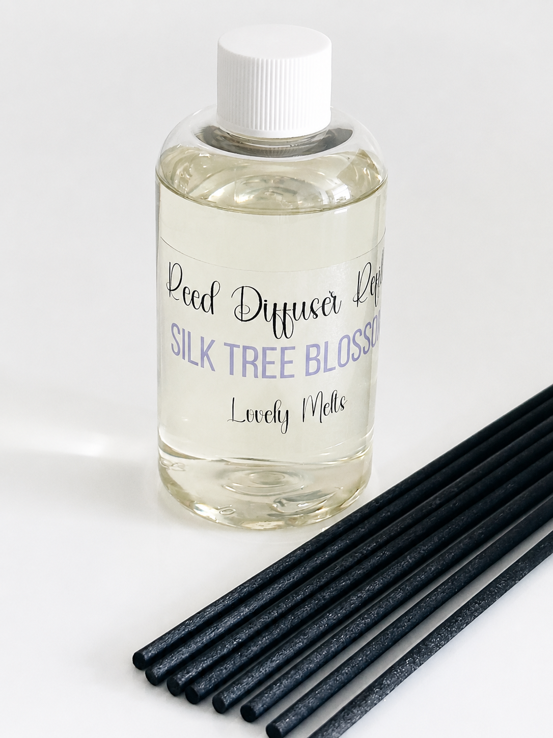 Bottle of 'Silk Tree Blossom' Reed Diffuser Refill with black reeds on a white background