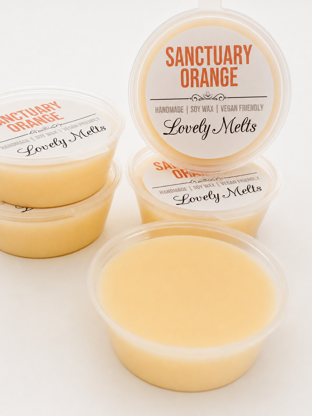 Four containers of 'Sanctuary Orange' Lovely Melts Wax Melts on a white background