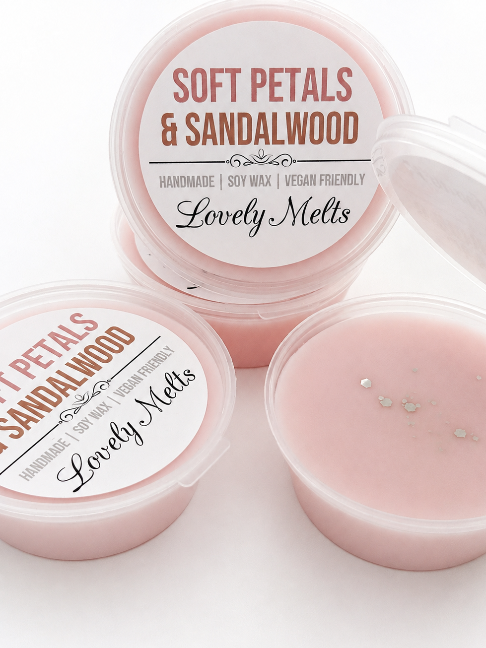 Three round plastic pots of Lovely Melts 'Soft Petals & Sandalwood' handcrafted soy wax melts, showing the pale pink wax inside and the white labels on the lids.