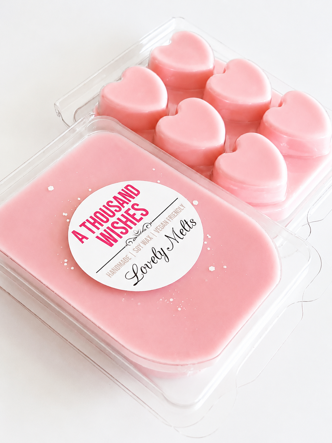 Pink heart-shaped wax melts in a container with 'A Thousand Wishes' label.