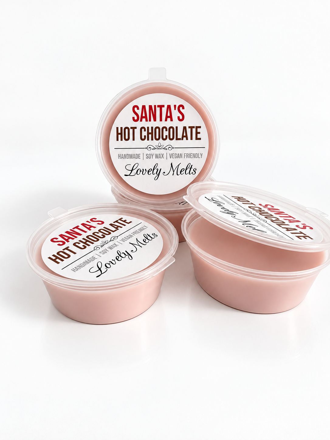 Three round plasticpots of hot chocolate wax melts with clear lids, arranged on a white background. One tub is standing upright with its label facing forward, and two more are angled in front, showing the label that reads 'Santa's Hot Chocolate' and 'Lovely Melts'.